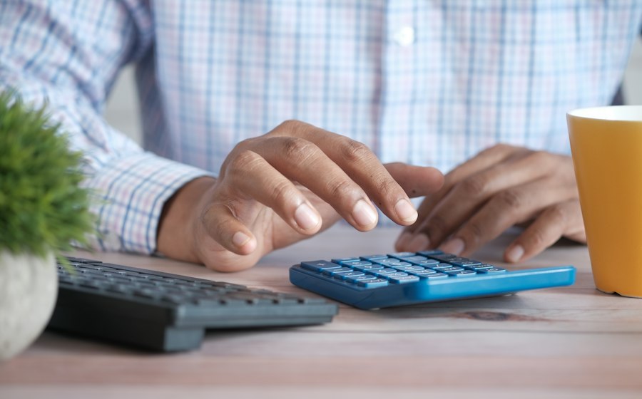 Hands working a calculator at a desk