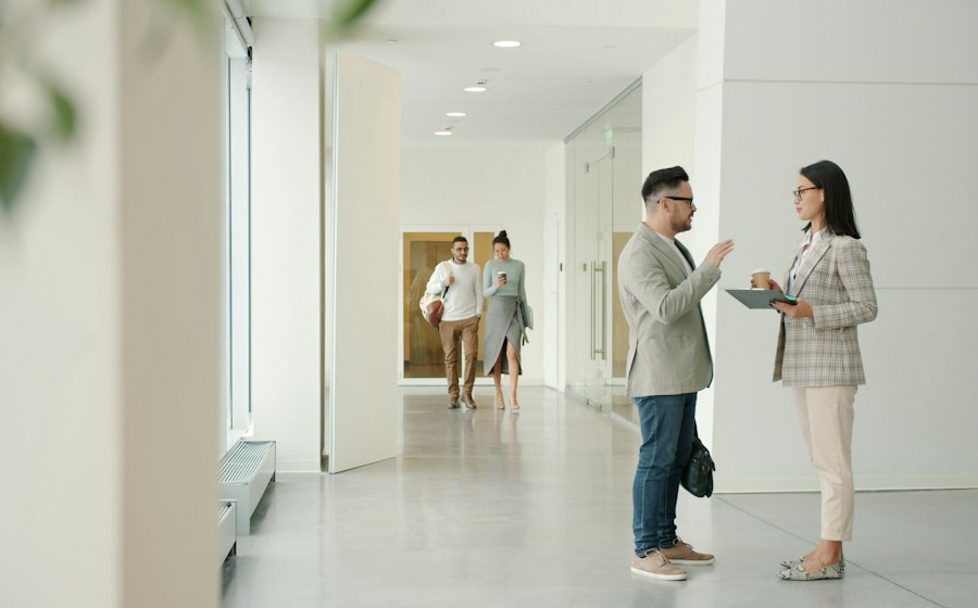 Two colleagues talking in a bright office hallway